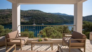 Un balcó amb vista a un llac i a les muntanyes, moblat amb dos sofàs i una taula.