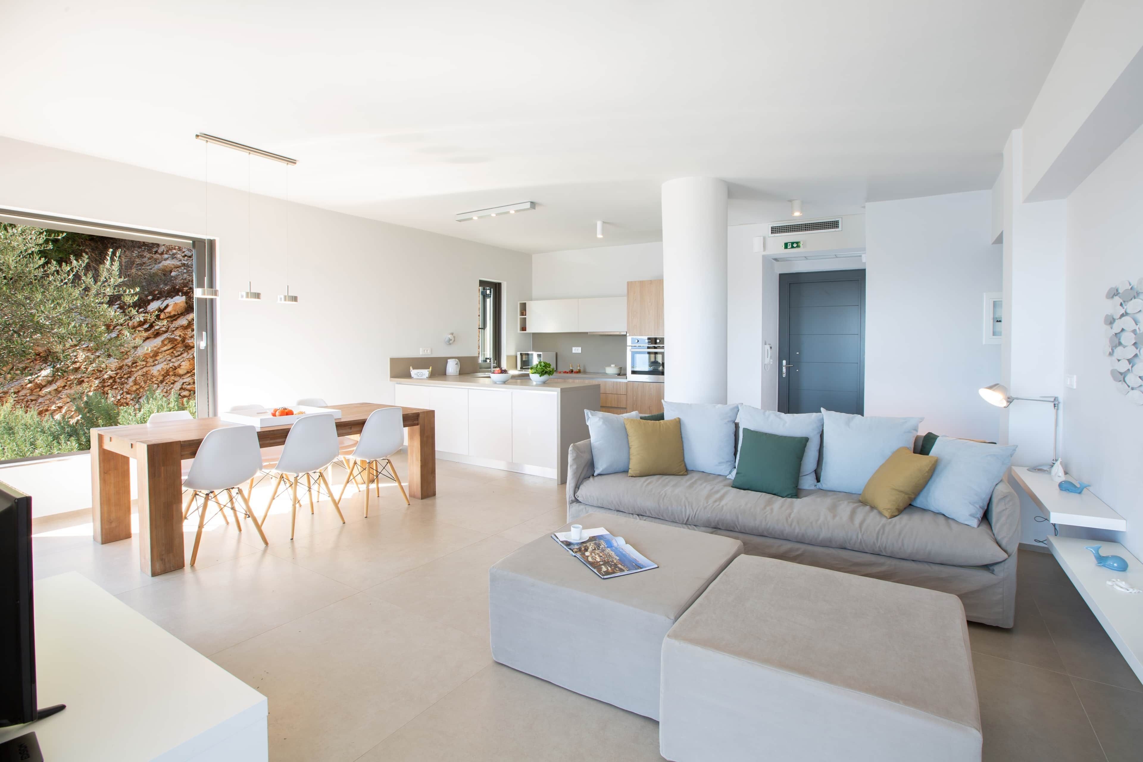A modern living room with a sofa, ottoman, and dining area.