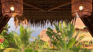 A thatched-roof structure with a garden path leading to a beach. - Tongo Hill Cottages (Moalboal)
