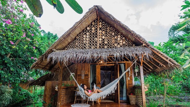 A wooden structure with a thatched roof, a hammock, and a garden. - Tongo Hill Cottages (Moalboal)