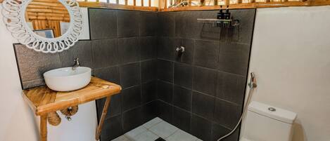 Ein Badezimmer mit Holzboden, einem weißen Waschbecken, einem Spiegel und einer Toilette.