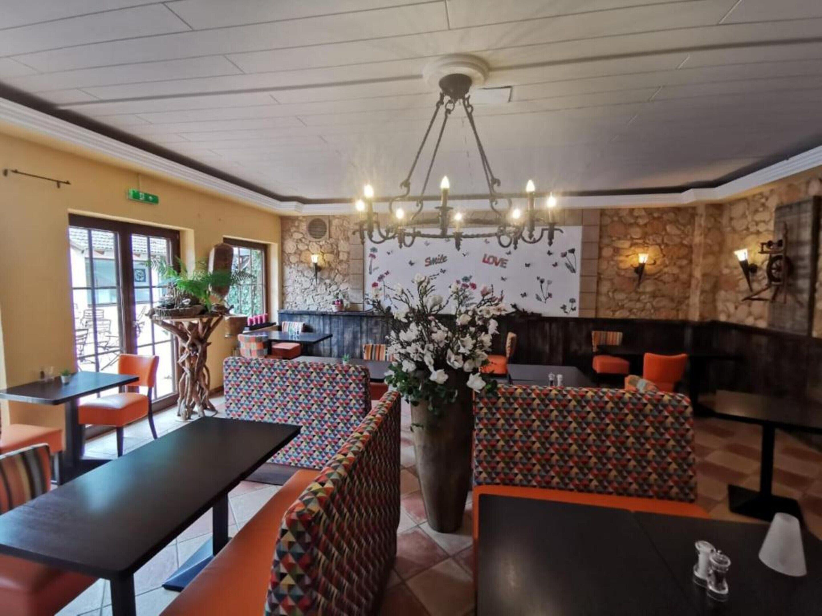 A restaurant with booths, tables, and a decorative wall with floral patterns.