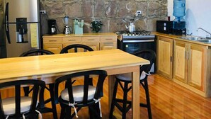 A modern kitchen with a stone wall, wooden cabinets, a stainless steel refrigerator, a coffee maker, and a water dispenser. - sunrise high above the lake 1 (San Pedro La Laguna)