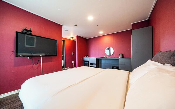 Habitación de hotel con una cama grande, televisor montado en la pared, escritorio con espejo y armario.
