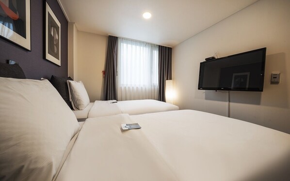 A hotel room with two beds, a flat-screen TV, a window with curtains, and framed artwork on the wall. - Myeongdong Young Inn Hotel (Seoul)