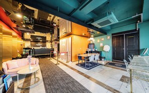 A modern hotel lobby with a sofa, a coffee table, a dining area, and a reception desk. - Myeongdong Young Inn Hotel (Seoul)