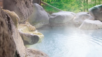 Une source thermale entourée de gros rochers.