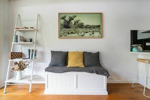 A room with a white bench, a bookshelf, and a framed picture on the wall. - Sleek Tempe Pad near SYD Airport & Transit (Tempe)