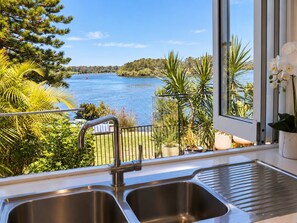 A kitchen with a view of a lake and surrounding greenery.