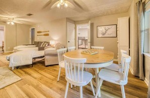 A cozy room with a bed, a sofa, a dining table with chairs, a ceiling fan, and a framed picture on the wall. - Lakefront, Boat Dock, Game Room, Backyard Oasis (Gainesville)