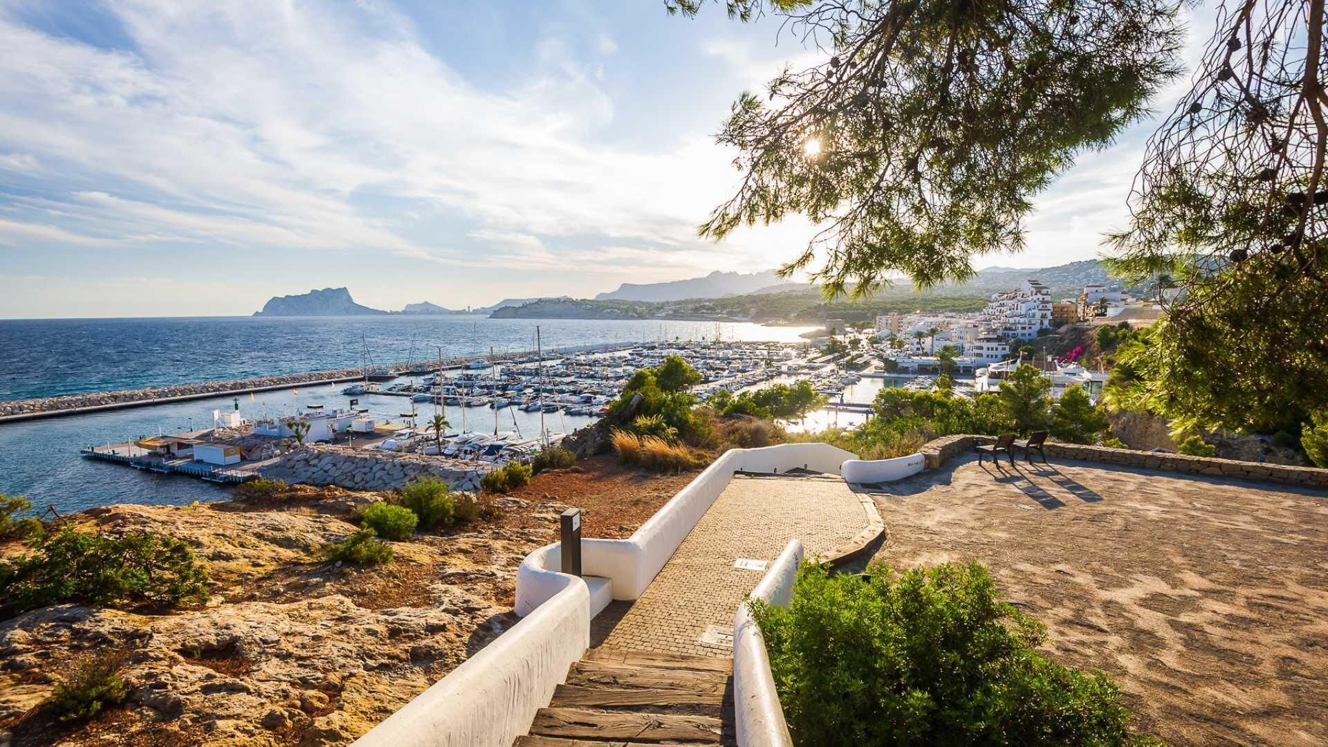 Une vue sur la côte, avec un port de plaisance, un escalier en pierre et un sentier menant à une plage.