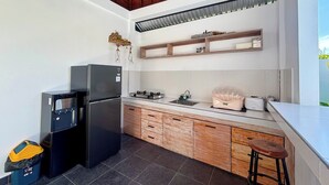 Una cocina compacta con refrigerador empotrado, estufa y muebles de madera.