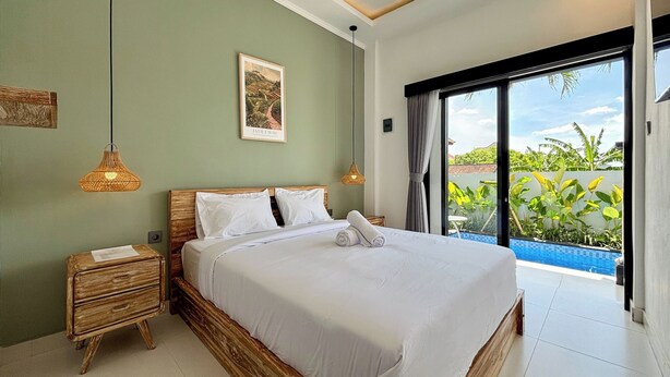 Un dormitorio con cama, mesitas de noche, un cuadro y vistas a una piscina.