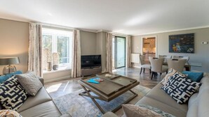 Una sala de estar moderna con sofá, mesa de centro, televisor y comedor.