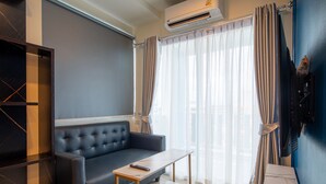 Una sala moderna con un sofá, una mesa de centro, un televisor y un equipo de aire acondicionado.