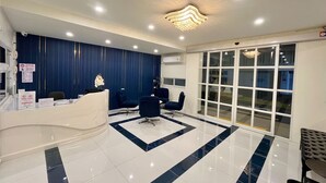 Un área de recepción con pared azul, una araña y un ventanal grande.