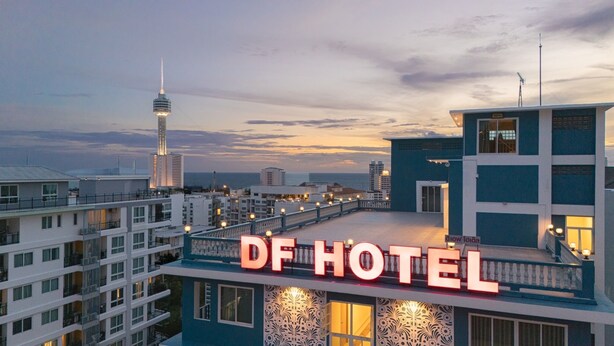 Un hotel con un llamativo letrero 'DF HOTEL', arquitectura moderna y vistas del horizonte de la ciudad.