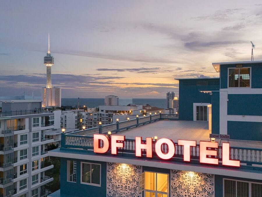Un hotel con un llamativo letrero 'DF HOTEL', arquitectura moderna y vistas del horizonte de la ciudad.