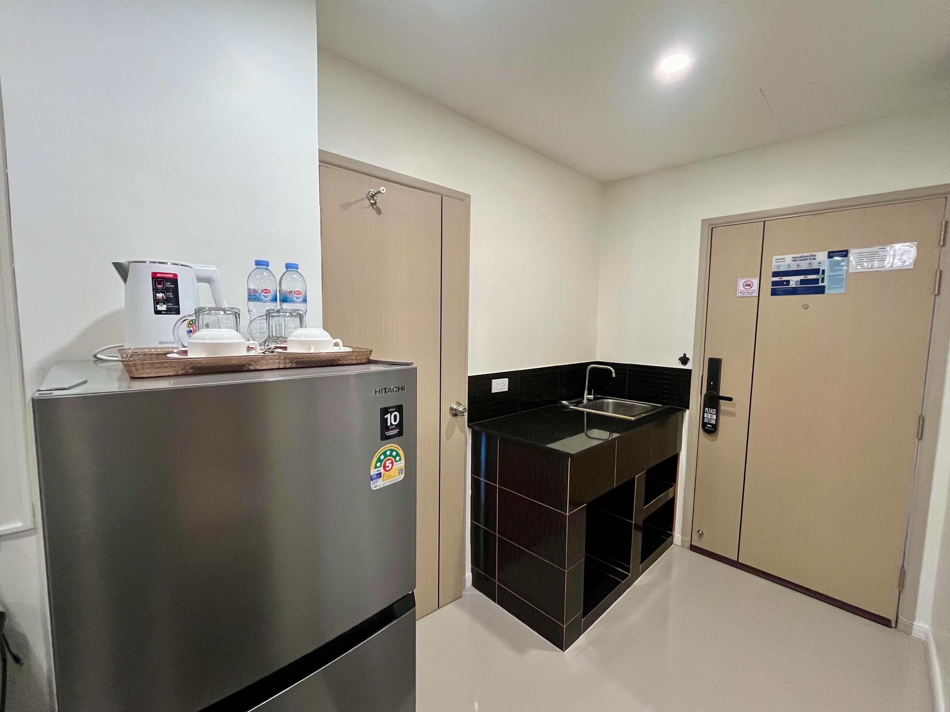 A compact kitchen with a refrigerator, a coffee maker, and a sink.