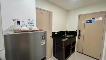 A compact kitchen with a refrigerator, a coffee maker, and a sink.