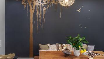 A dining area with a wooden table, a vase with a plant, and a decorative wall mural.