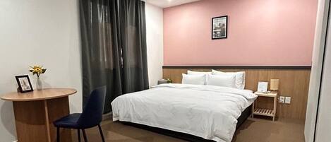Habitación de hotel con cama, escritorio, silla, mesita de noche y un cuadro en la pared.