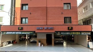 Un hotel de dos pisos con un letrero que dice 'BROWN-DOT HOTEL' y un cartel de estacionamiento.