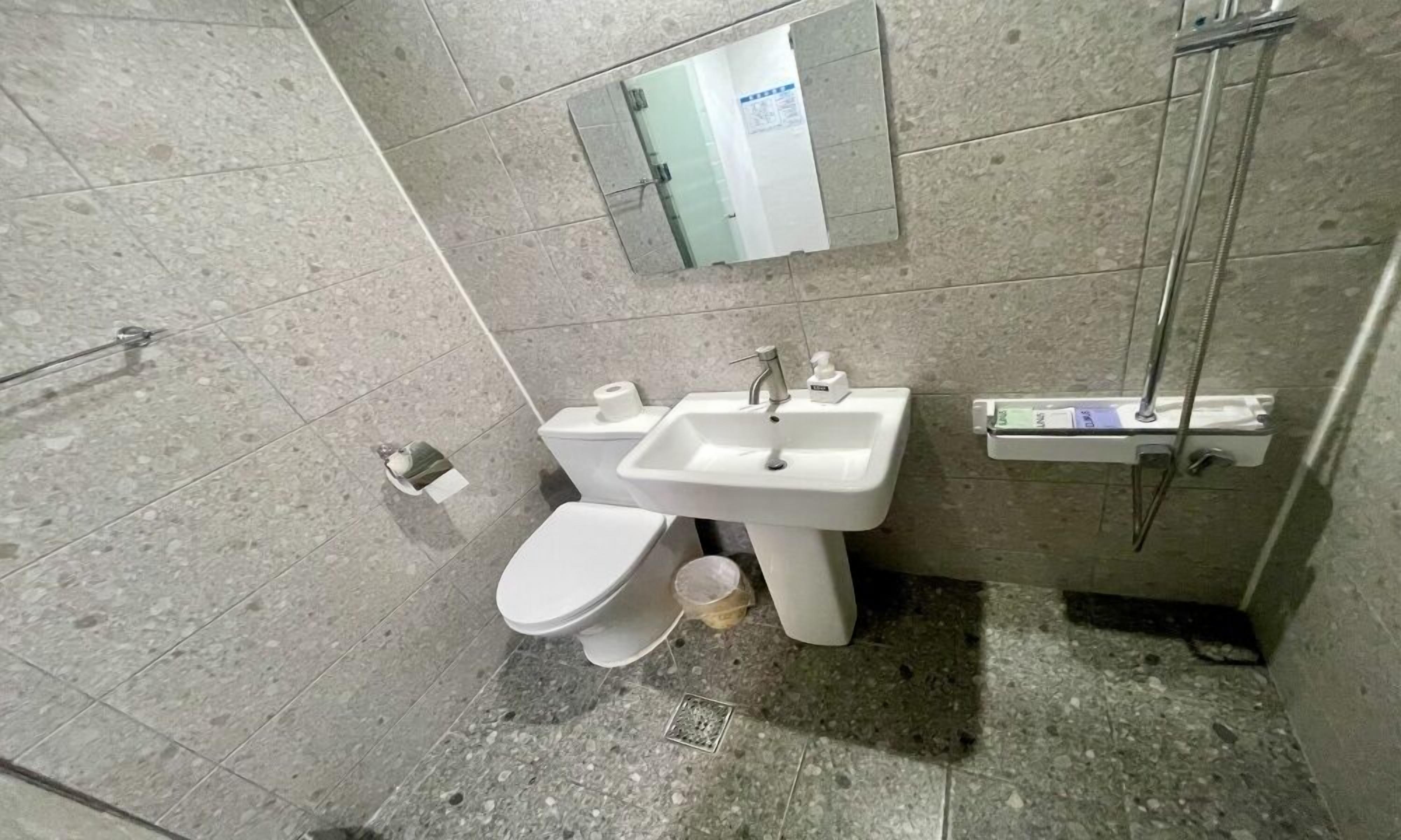 Un baño con inodoro, lavabo, espejo y ducha.