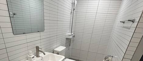 A small bathroom with a sink, toilet, and shower.