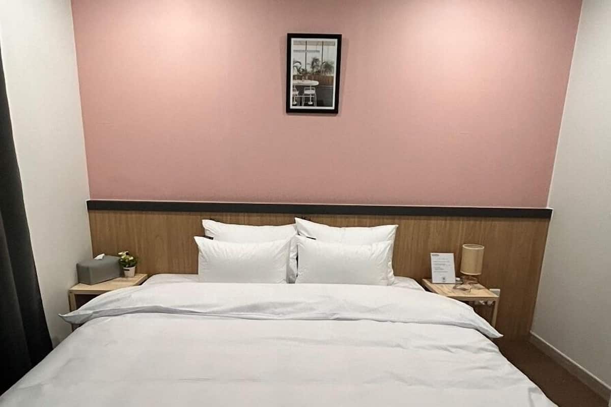 Una habitación de hotel con una cama, una mesita de noche, una lámpara y un cuadro en la pared.