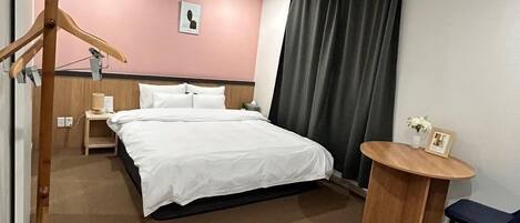 A hotel room with a bed, bedside table, lamp, and a small round table with a chair.