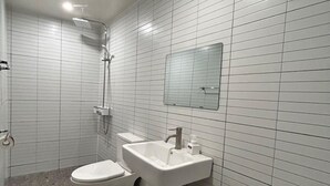 Un baño pequeño y moderno con inodoro, lavamanos y ducha.