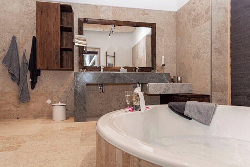 A modern bathroom with a freestanding bathtub, a marble countertop, and a large mirror.