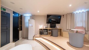A modern hotel room with a flat-screen TV, a minibar, a seating area, and a large window with curtains. - Brown Dot Hotel Pyeongtaek Godeok (Pyeongtaek)