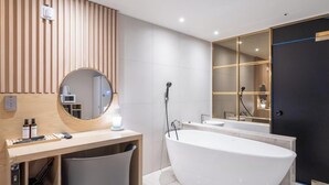 A modern bathroom with a freestanding bathtub, a vanity with a mirror, and a large mirror above the tub. - Brown Dot Hotel Pyeongtaek Godeok (Pyeongtaek)