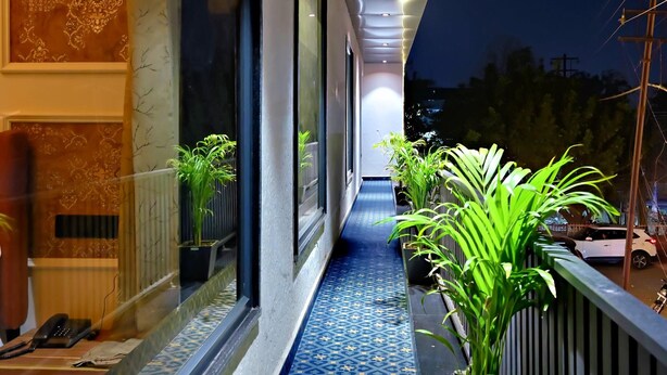 A corridor with patterned flooring, potted plants, and a view of the outside. - Homestay By cafe9 (Amritsar)