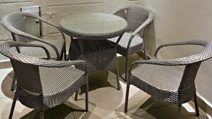 A corner room with a textured wall, a round table, and four wicker chairs. - Homestay By cafe9 (Amritsar)
