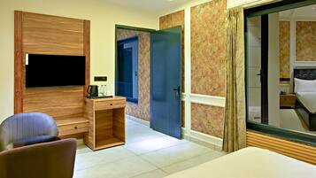 Een hotelkamer met televisie, bureau, stoel en een bed.