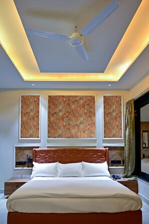 A bedroom with a bed, ceiling fan, wall-mounted artwork, and a window with curtains. - Homestay By cafe9 (Amritsar)
