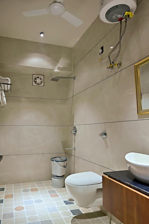 A modern bathroom with a toilet, sink, shower, ceiling fan, and towel rack. - Homestay By cafe9 (Amritsar)