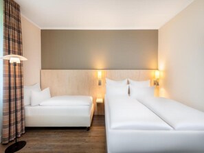 A hotel room with two beds, a large wall-mounted light, and a floor lamp. - Sunday Bielefeld Standard Double Room (Bielefeld)