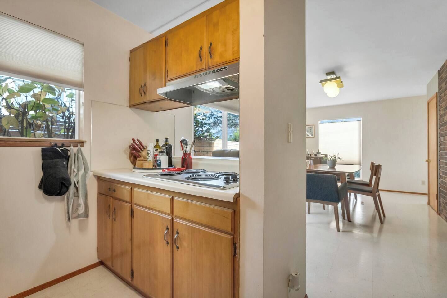 A compact kitchen with wooden cabinets, a stove, and a window with a view.