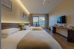 Une chambre d’hôtel avec deux lits, un bureau doté d’un téléviseur à écran plat, une grande fenêtre offrant une vue agréable et une tête de lit en bois.