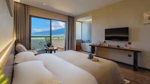 Une chambre d’hôtel avec un grand lit, une télévision, un bureau et une vue sur le paysage urbain.