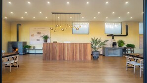 Un espace d’accueil doté d’un comptoir de réception en bois, de luminaires suspendus, d’une cheminée et de plantes en pot.