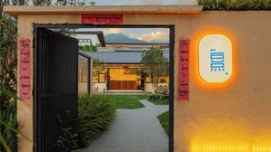 Une entrée d’immeuble avec un portail noir, un chemin menant à l’immeuble et une enseigne avec des caractères chinois.