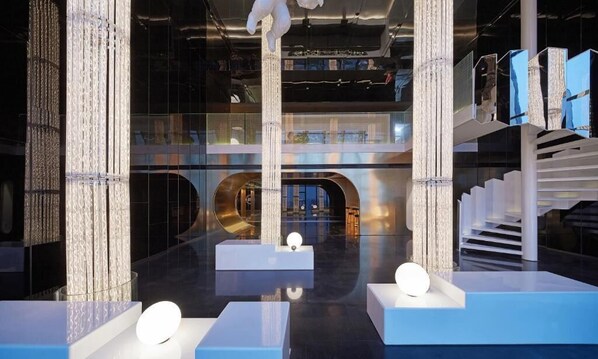 A modern interior with reflective surfaces, geometric columns, and a central staircase. - SEYA Panoramic Hotel - Chengdu Tianfu Square Chunxi Road - Managed by SEYA GROUP (Chengdu)