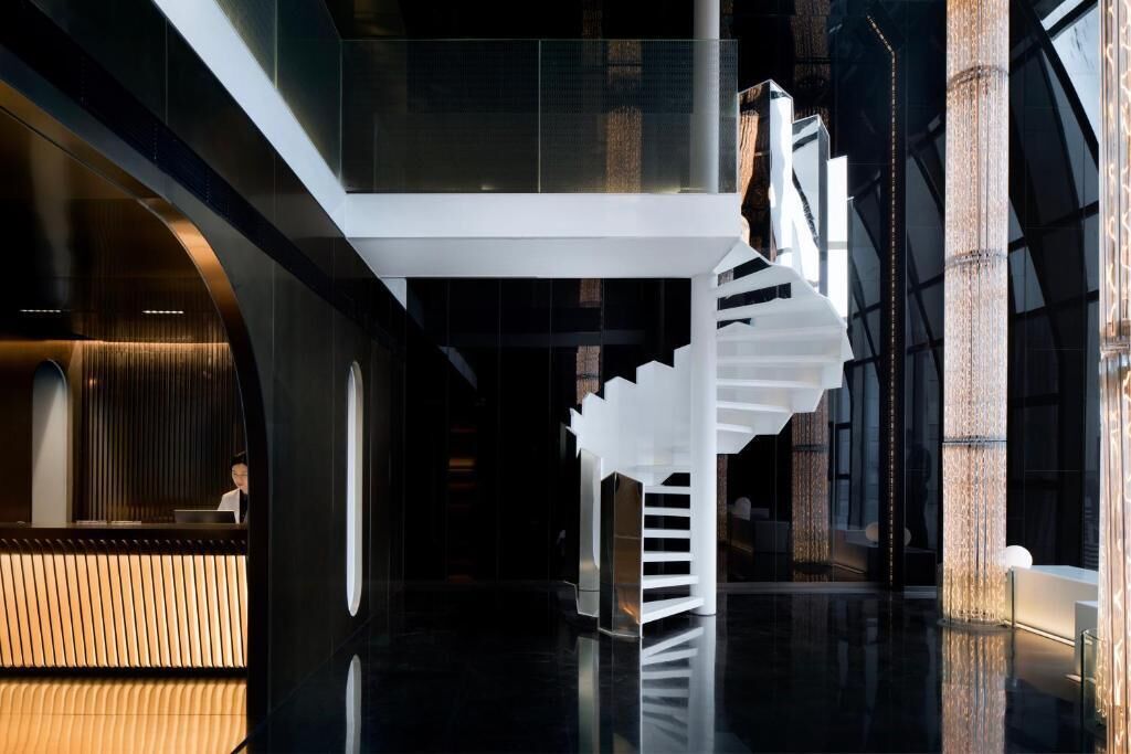 Un interno moderno con una scala in vetro, una reception e un pavimento lucido.