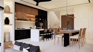 Una cocina moderna con electrodomésticos integrados, una zona de comedor con una mesa y sillas, y una escalera que sube a un nivel superior.