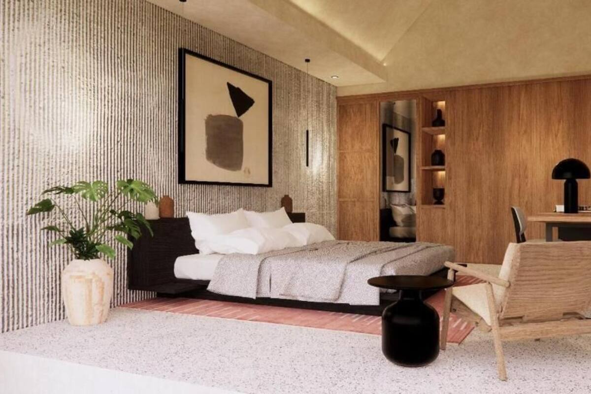 Un dormitorio moderno con una cama, una silla, una mesita, una planta en maceta y una obra de arte enmarcada en la pared.